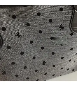 Close-up of grey herringbone fabric tote with black polka dots and small bow detail