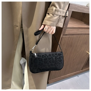 Close-up of black leopard print suede shoulder bag with metallic zipper on a model