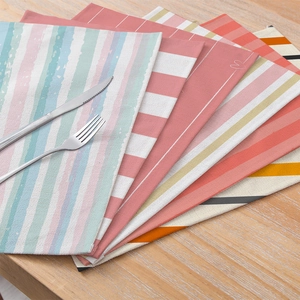 Striped cotton linen placemats set displayed on a wooden table with cutlery