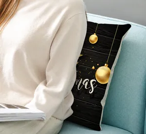 Detail of black Christmas pillow cover with golden festive ornaments on a blue sofa