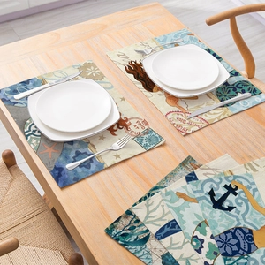 Marine life themed linen placemats featuring mermaids and anchors on a wooden dining table