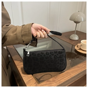 Detail of black leopard print textured handbag with silver zipper and shoulder strap