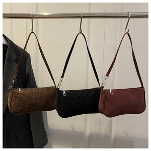 Close-up of three vintage baguette bags in leopard print and wine red on a display rack