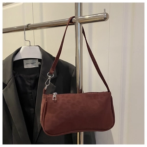 Detail of dark burgundy underarm bag featuring subtle leopard texture and silver zipper