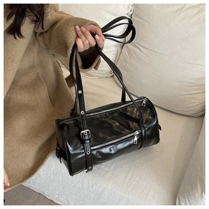 Detail of black glossy leather pillow bag with silver zippers and adjustable strap