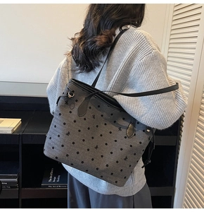 Detail of grey polka dot tote bag with black bows and long shoulder strap on a model
