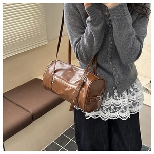Close-up of caramel brown pillow bag with polished leather texture and silver zipper details
