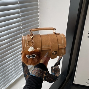 Brown barrel handbag with gold studs, vintage patterned strap and plush monster charm