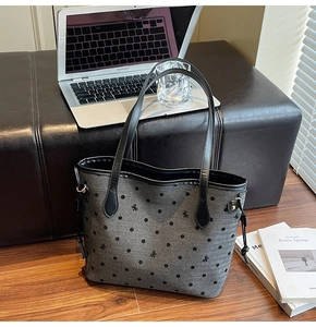 Detail of grey canvas tote bag with black dots, bow symbols and leather shoulder straps