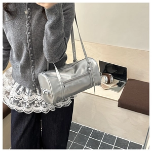Detailed view of silver metallic pillow bag with slim shoulder straps and zipper pocket