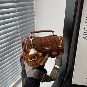 Detail of retro brown leather crossbody bag with gold rivets and bohemian strap