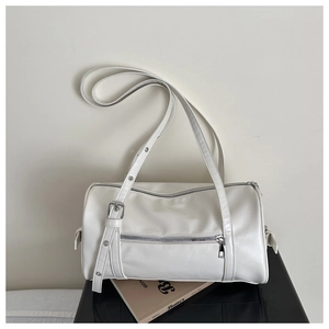 Close-up of white leather pillow bag with silver zipper and adjustable strap detail