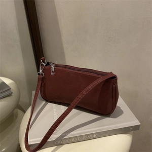 Minimalist matte dark red shoulder bag placed on a book with a clean studio background