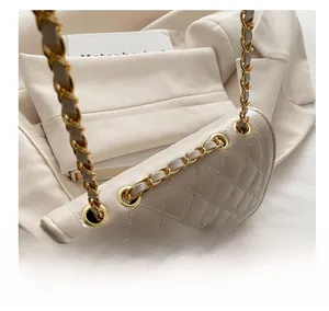 Close-up of beige quilted shoulder bag featuring gold chain strap and metal grommet details