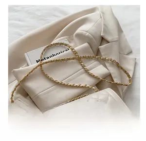 Detail of cream quilted leather bag with gold chain strap on a blazer background