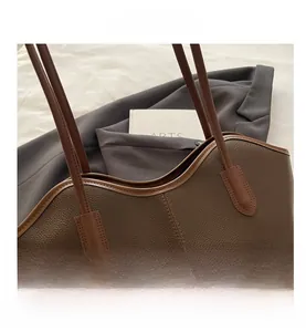 Detail of dark brown lychee texture leather tote bag with stylish contrast trim and strap
