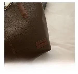 Detail of dark brown lychee leather texture and FASHION & BAGS tag on a tote bag