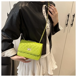 Detail of bright green quilted crossbody bag with gold twist lock on model