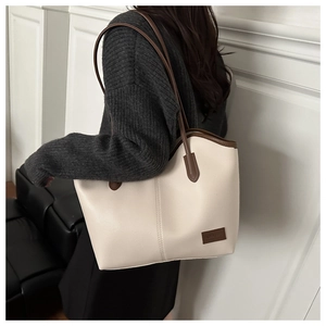 Detail of vintage tote bag showing off-white PU leather texture and brown strap