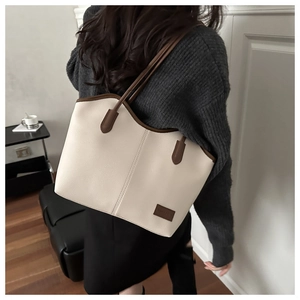 Detail of lychee textured leather and branded patch on a beige tote bag with brown straps