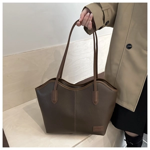 Macro detail of dark coffee leather tote bag with lychee texture and stitching