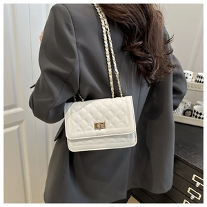 Rear view of a model wearing a white quilted leather shoulder bag with a gold chain strap
