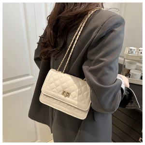Detail of quilted beige shoulder bag with gold chain strap on a grey blazer outfit