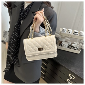 Detail of cream quilted crossbody bag with gold chain strap and metal turn-lock