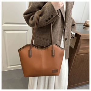 Detail of lychee pattern leather tote bag with wavy rim design and fashion logo label