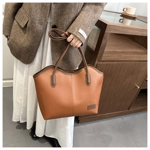 Close-up of vintage brown lychee leather tote bag featuring double shoulder straps
