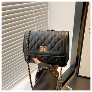 Detail of black quilted leather shoulder bag featuring a gold twist lock and chain strap
