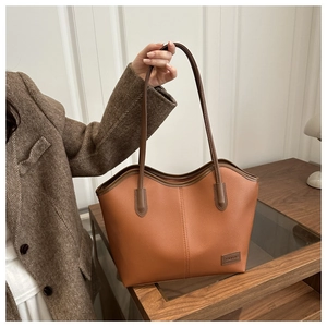 Close-up of pebble leather texture and stitched fashion brand label on a brown tote bag