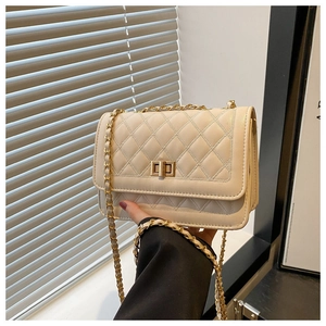Close-up of cream quilted crossbody bag featuring golden chain strap and metal turn-lock