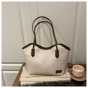 Detail of contrast stitching and brown leather logo on a cream pebble tote bag