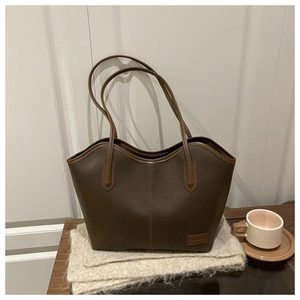 Detail of a large vintage brown tote bag with pebble leather texture and stitched label