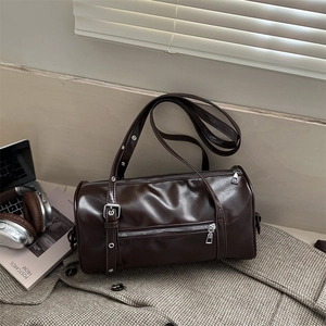 Deep brown cylindrical pillow bag with silver zipper on a checkered suit background