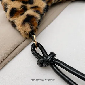 Detail of leopard print faux fur bag with black knotted leather strap and gold ring