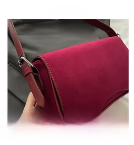 Detail view of burgundy faux suede shoulder bag with fine stitching and silver buckle