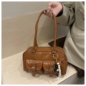 Detailansicht der braunen Retro-Tasche mit Vordertaschen und Perlen-Anhänger