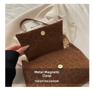 Detailed view of gold magnetic clasp and leopard print texture on a vintage tote bag
