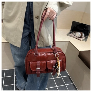 Detailansicht der burgunderroten Lackleder-Boston Bag mit Perlenanhänger und Außentaschen