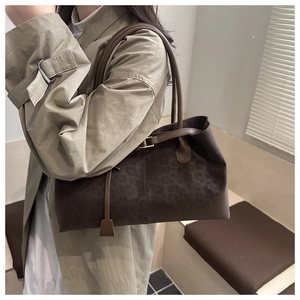 Macro detail of dark brown leopard print suede tote with leather straps and buckles