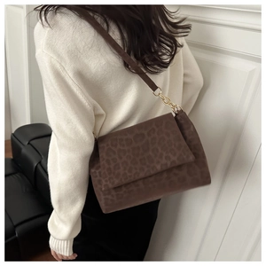 Brown leopard print shoulder bag with gold chain strap detail shown on a model