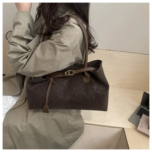 Detail of suede leopard print tote bag with brown leather strap worn by a model