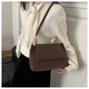 Detail of leopard print shoulder bag featuring textured finish and gold chain accents