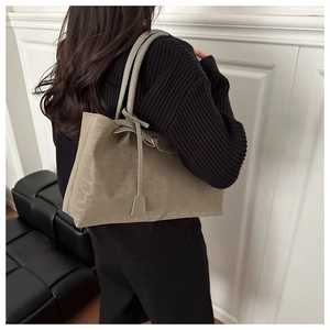Detail of a large khaki faux suede tote bag with long handles and a metal buckle charm