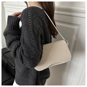 Detail view of cream matte underarm bag on shoulder with sleek curved flap design