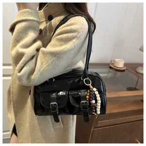 Details einer glänzenden schwarzen Umhängetasche mit zwei Taschen und Vintage-Holzperlen