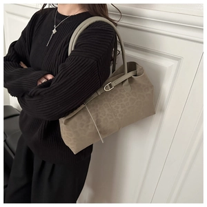 Detail of taupe suede tote bag with leopard print texture on a black sweater