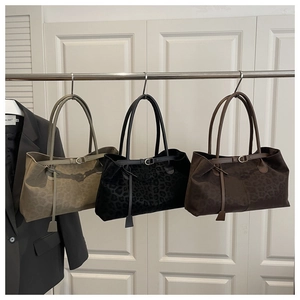 Three suede tote bags with leopard embossing hanging in a minimalist studio setup